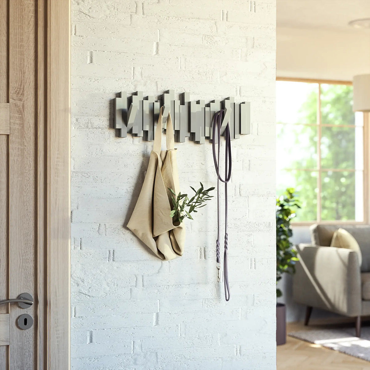 Umbra Sticks 5 hook rack in grey by a door holding a linen jacket and a leash