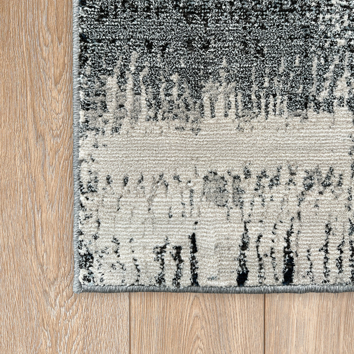 Corner of the blue and ivory abstract rug on a timber floor