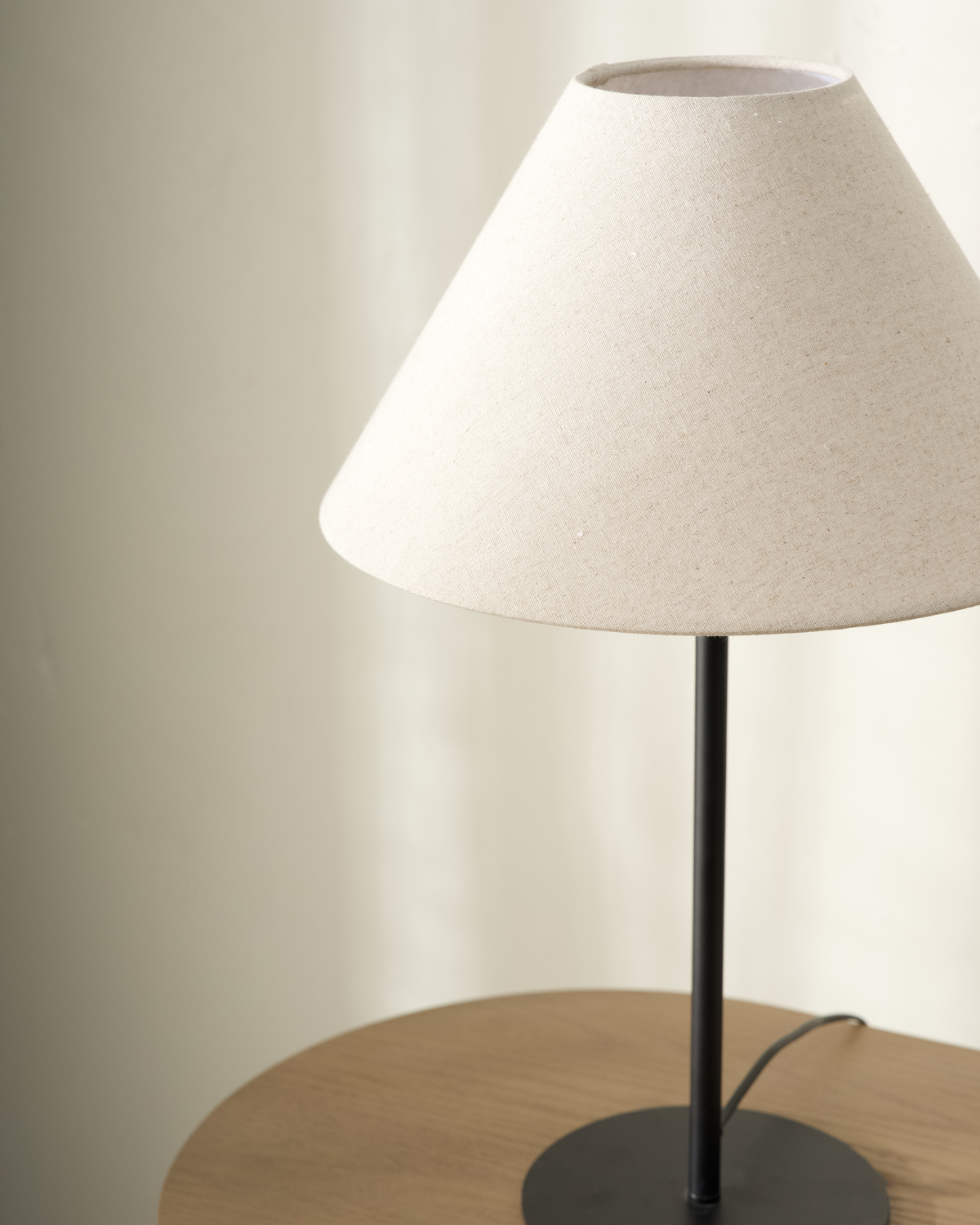 Close-up of Arch Table Lamp showing natural linen shade, slim black stem and round black base