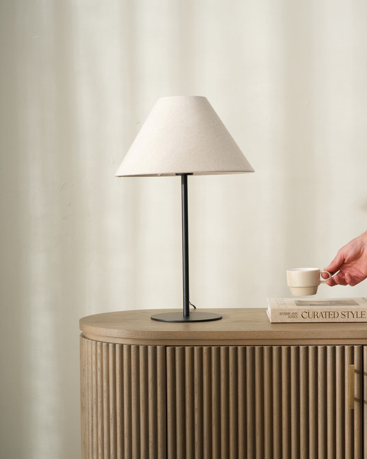 Arch Table Lamp with linen shade styled on a timber sideboard beside books and a cup