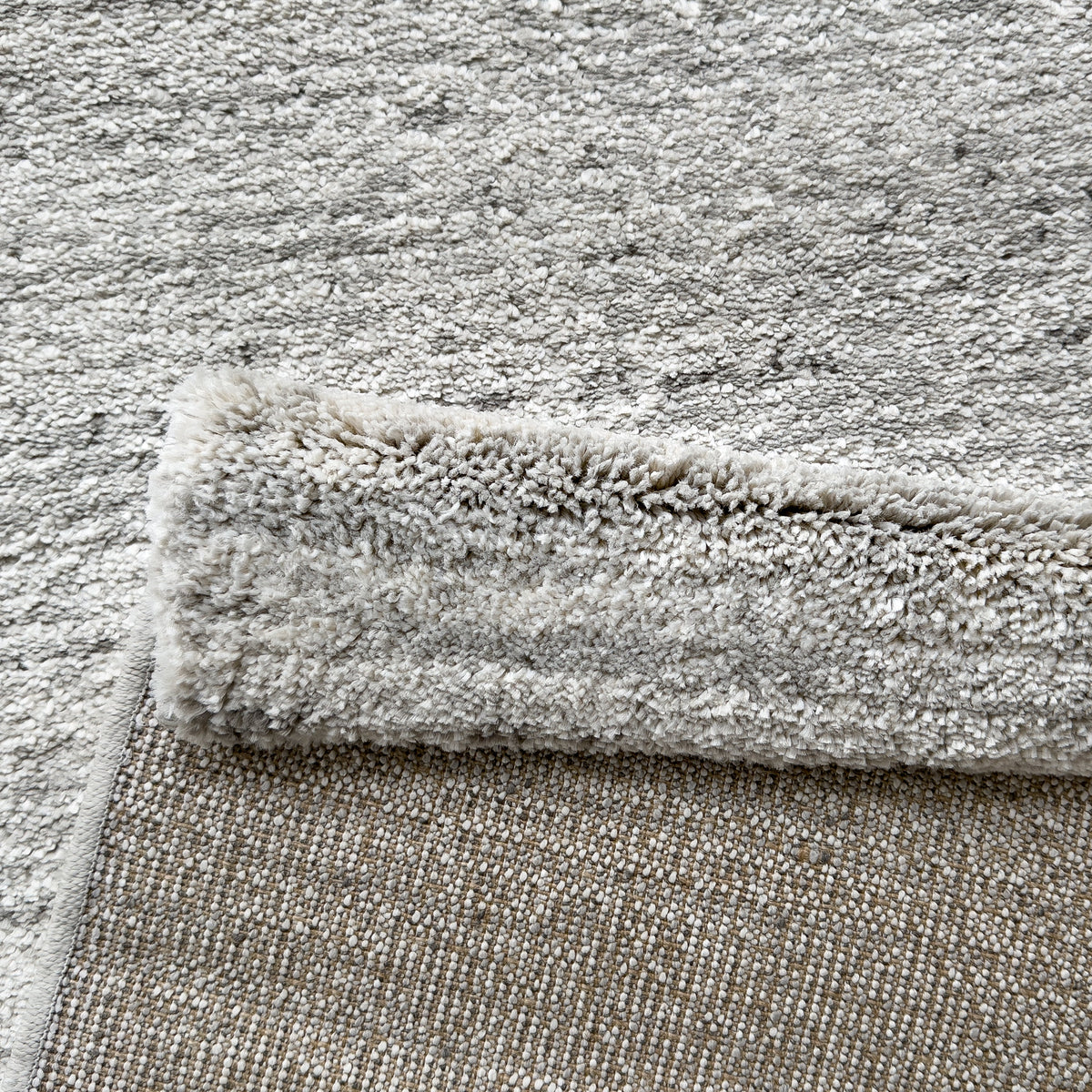 Folded corner showing the pale grey pile and the woven backing