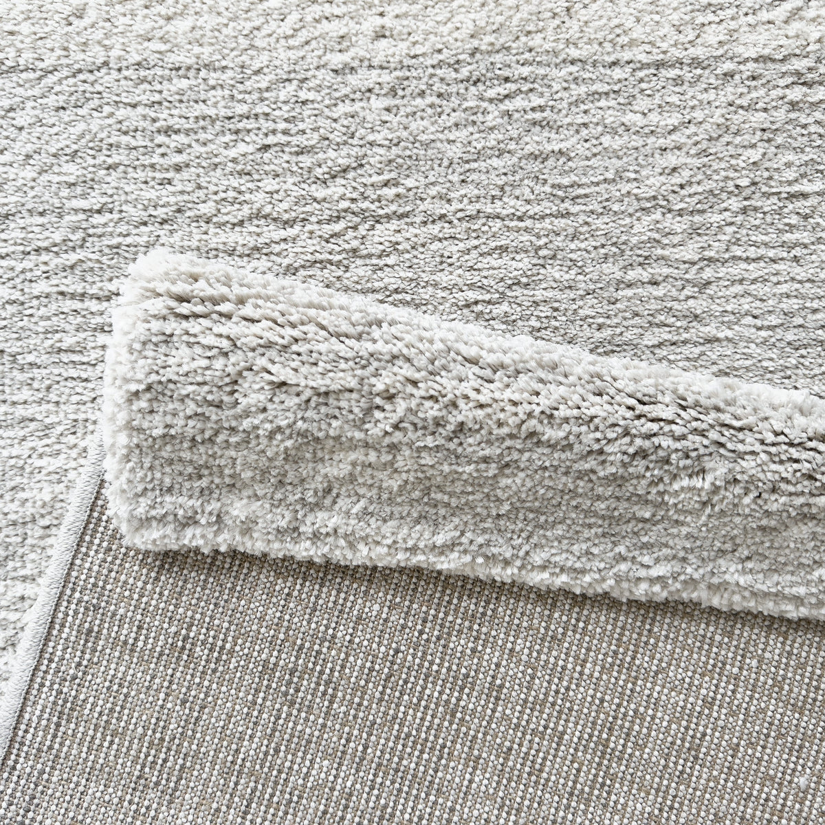 Folded corner showing the soft grey pile and the woven backing
