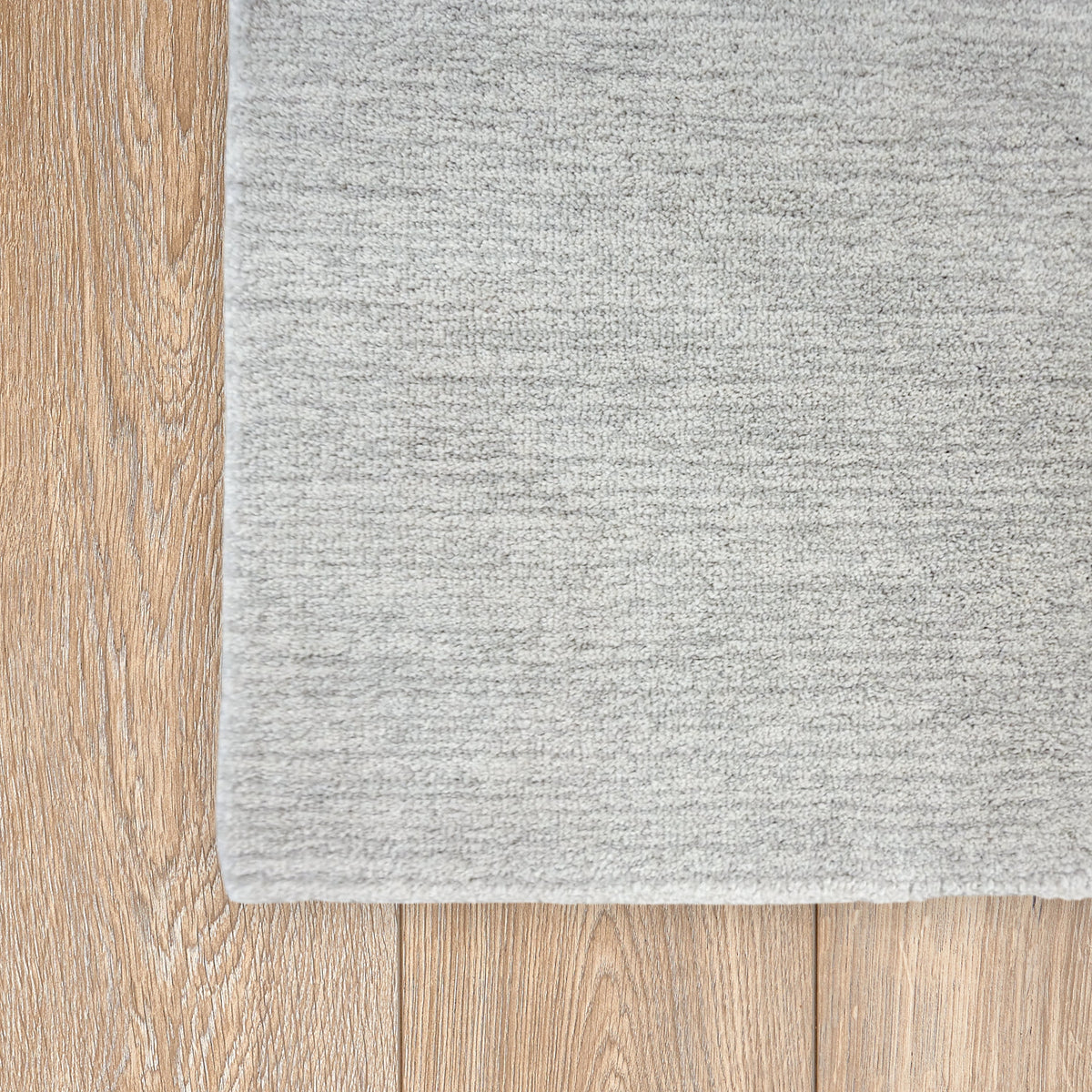 Corner of the soft grey rug on a light timber floor