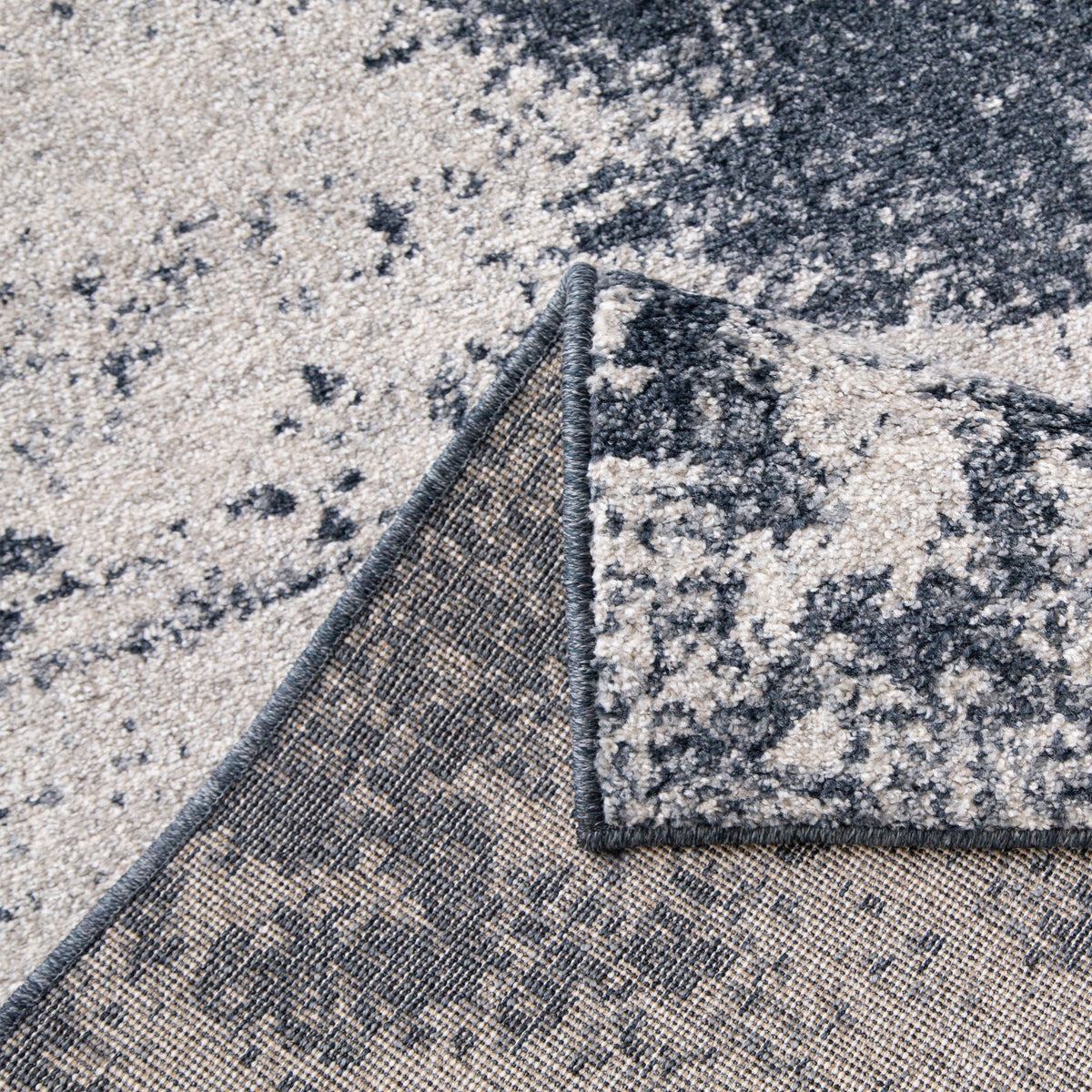 Dark blue and cream rug folded back to show the woven backing