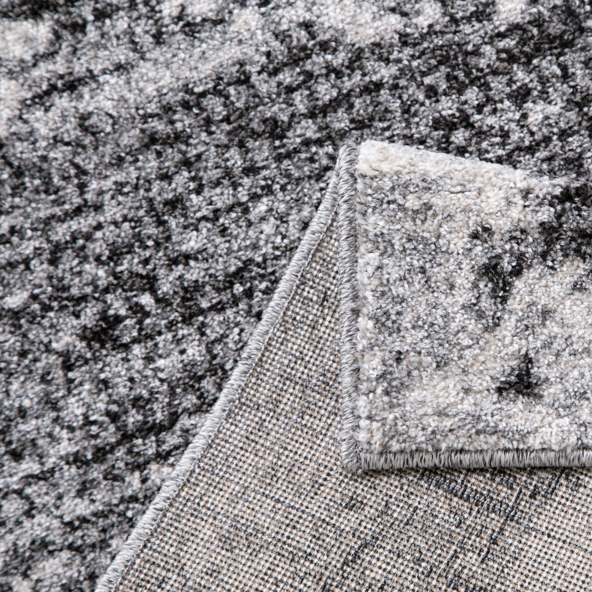 Light grey and black rug folded back to show its woven backing