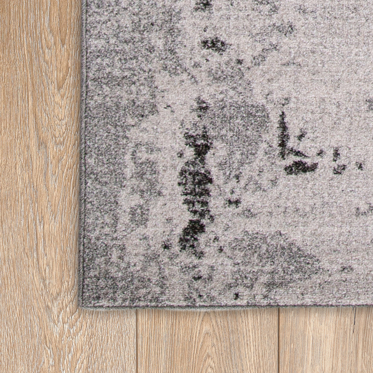 Corner of the light grey and black rug on a timber floor