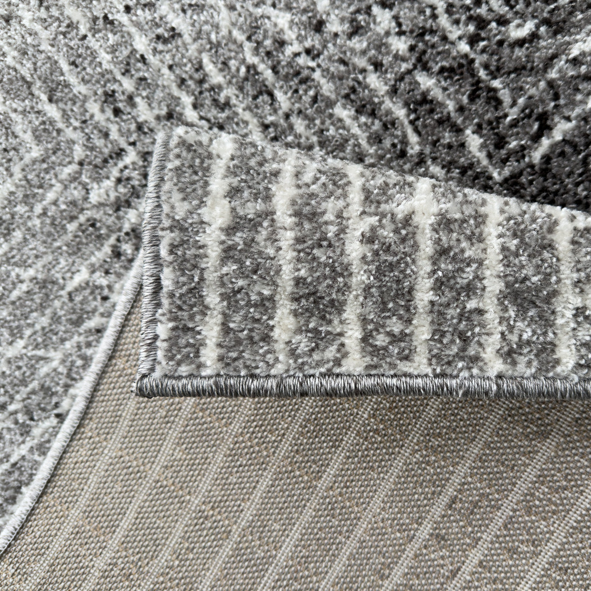 Folded corner showing the charcoal and white pile and the woven backing