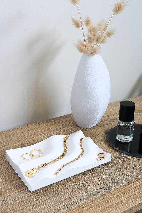 A Tidal Tray, made by Utilize Studios, featuring a collection of gold jewelry and a vase placed elegantly on top.