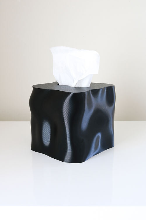 Glossy black Ebb tissue box cover with a tissue drawn through, on a white table