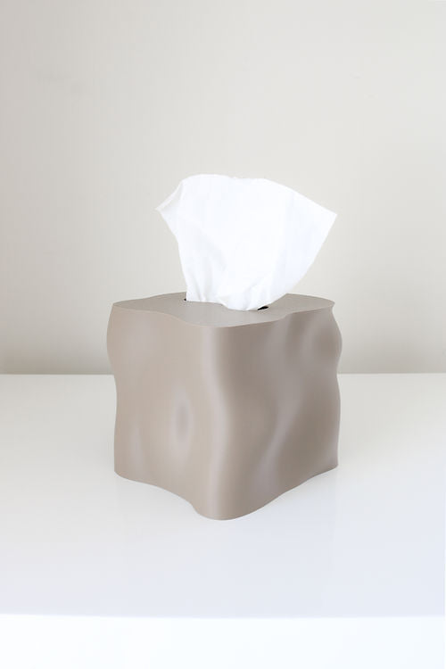 Taupe Ebb tissue box cover on a white surface with a tissue drawn up through the opening