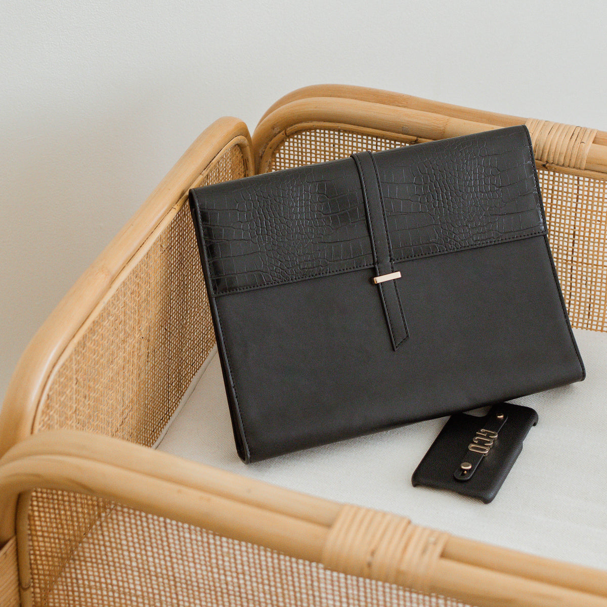 Black Penelope laptop sleeve on a rattan chair