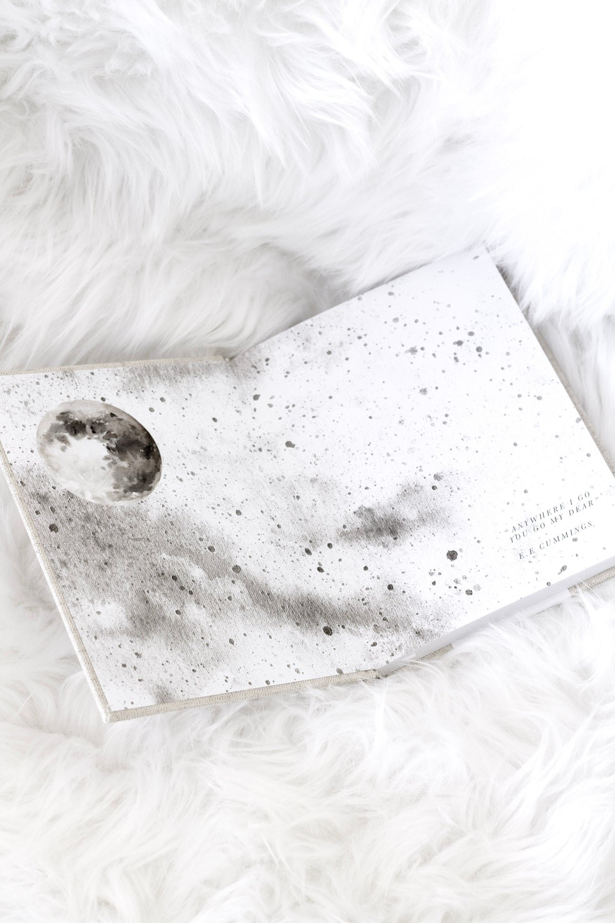 Bump journal open to its moon artwork endpapers on white faux fur
