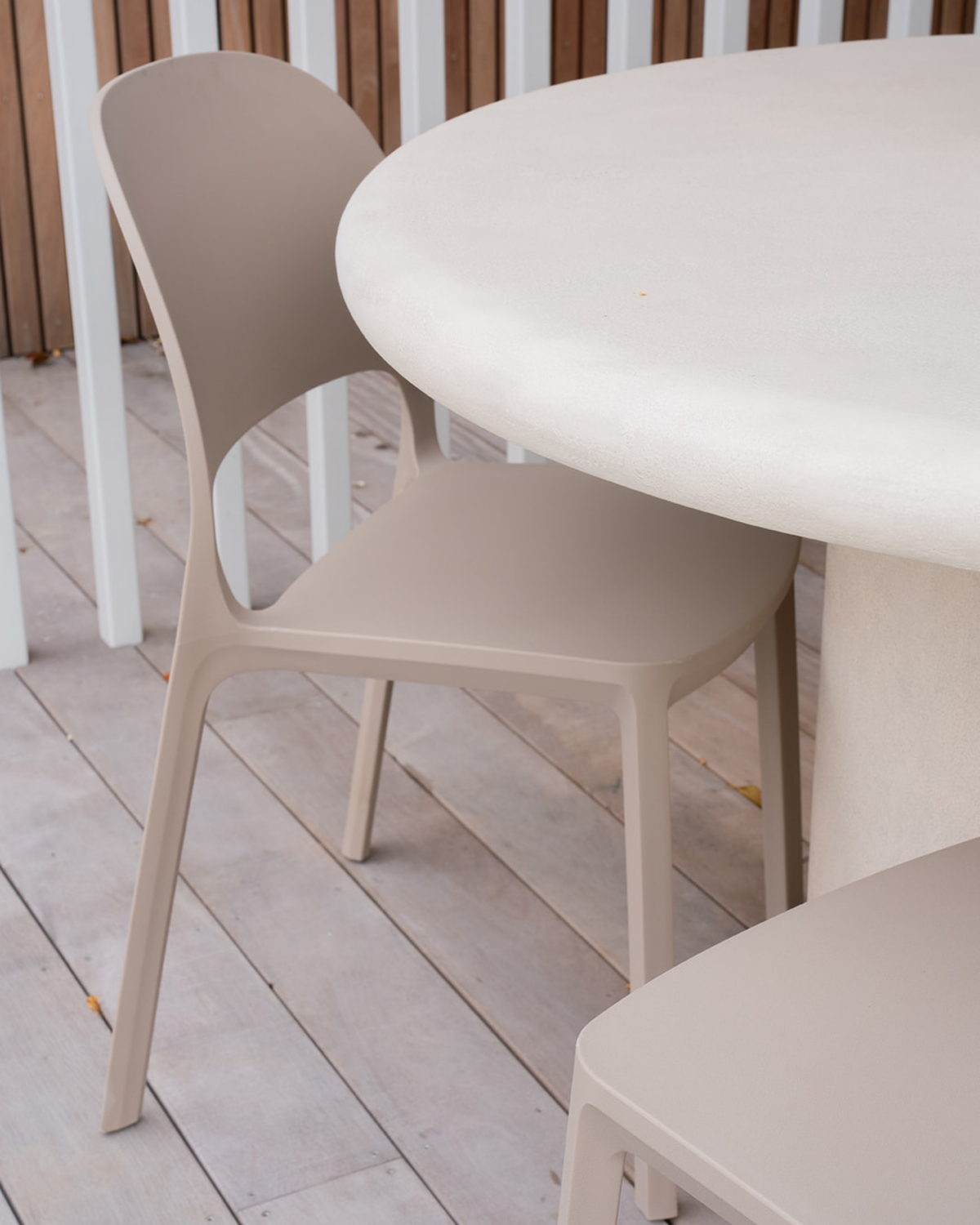 Close view of a Nude Cali chair tucked under a round table, showing the moulded back and seat