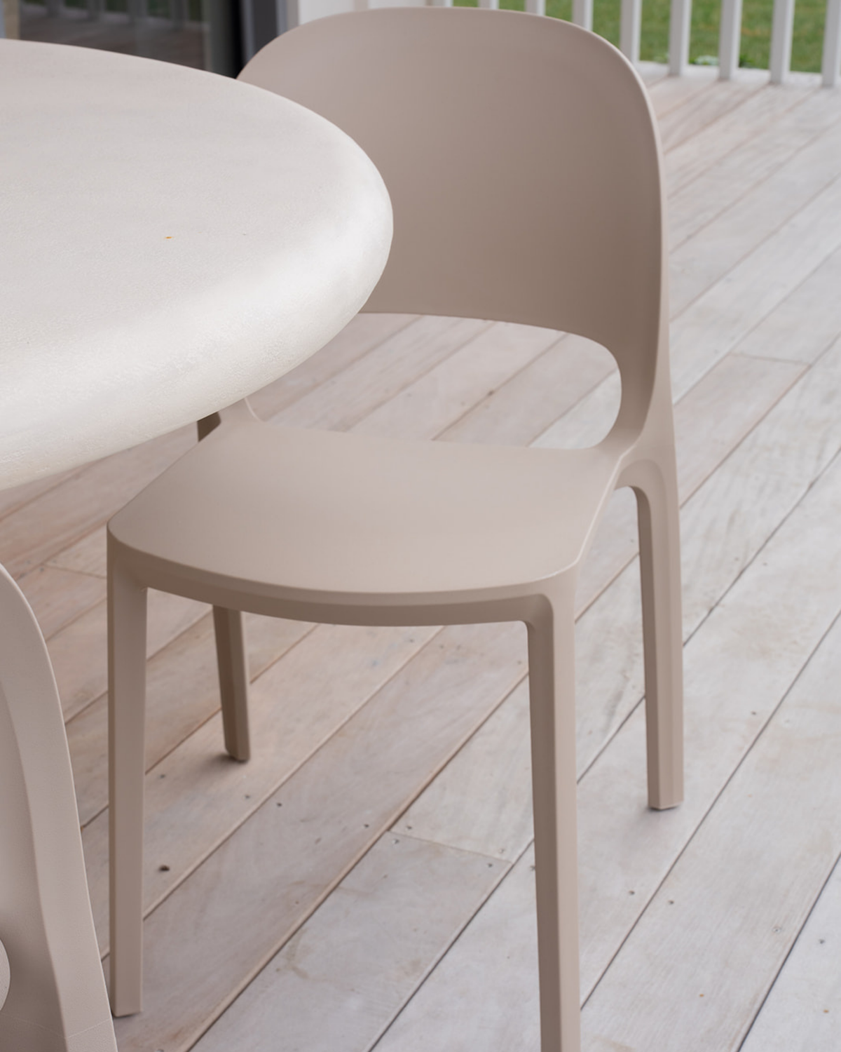 Nude Cali chair seat and legs on limed timber decking beside a pale round tabletop