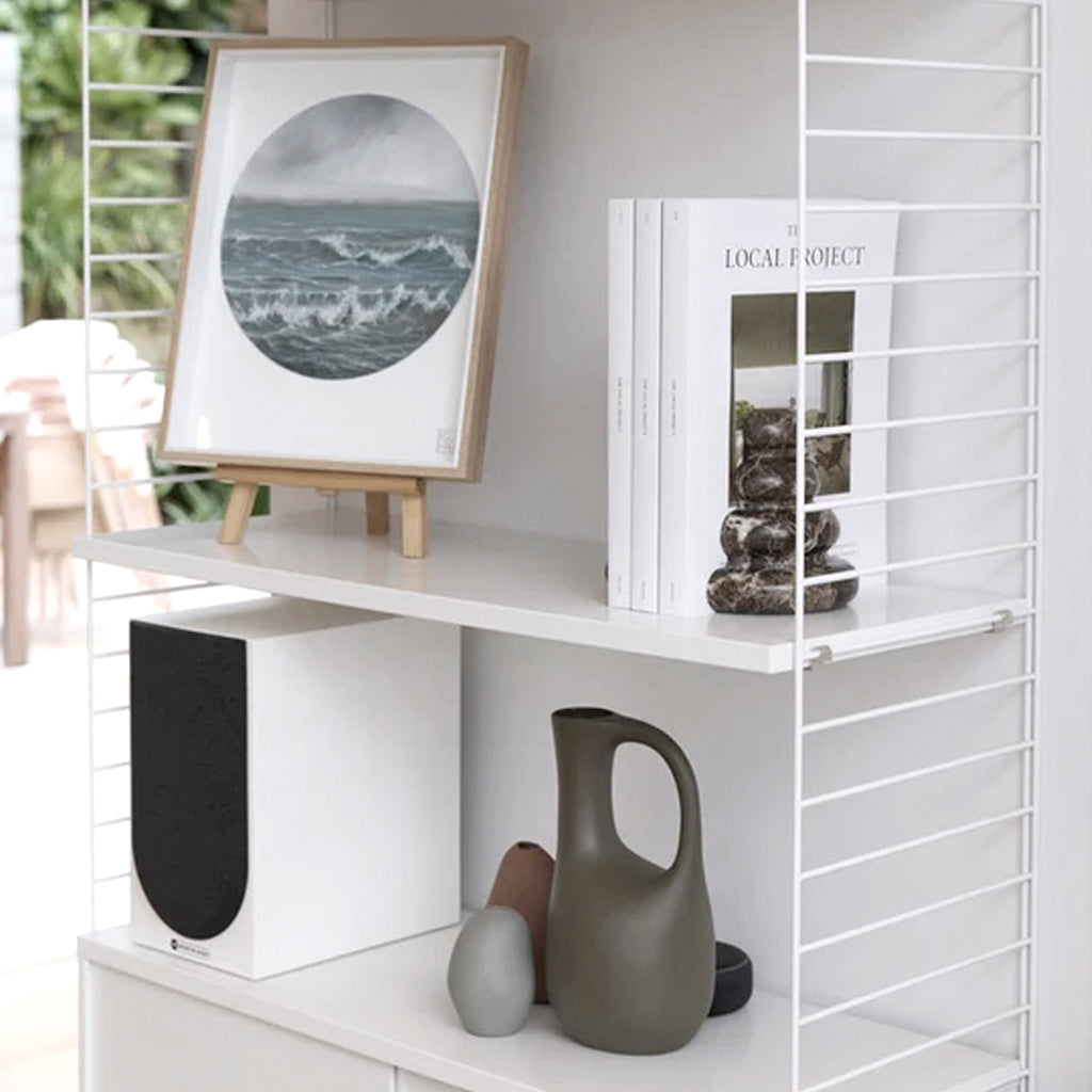 Casa bookend on a white wall shelf beside a framed print and sculptural vases
