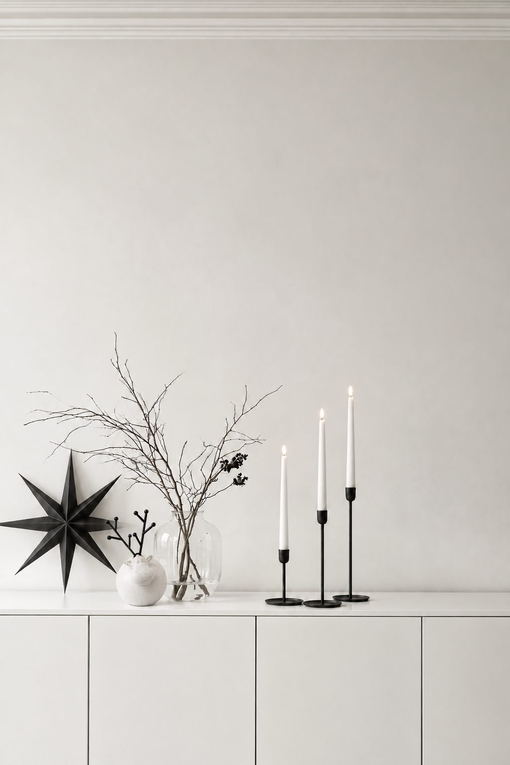 Ceramic Deer with Metal Antlers 15cm on a white sideboard beside a black star, bare branches and black candlesticks