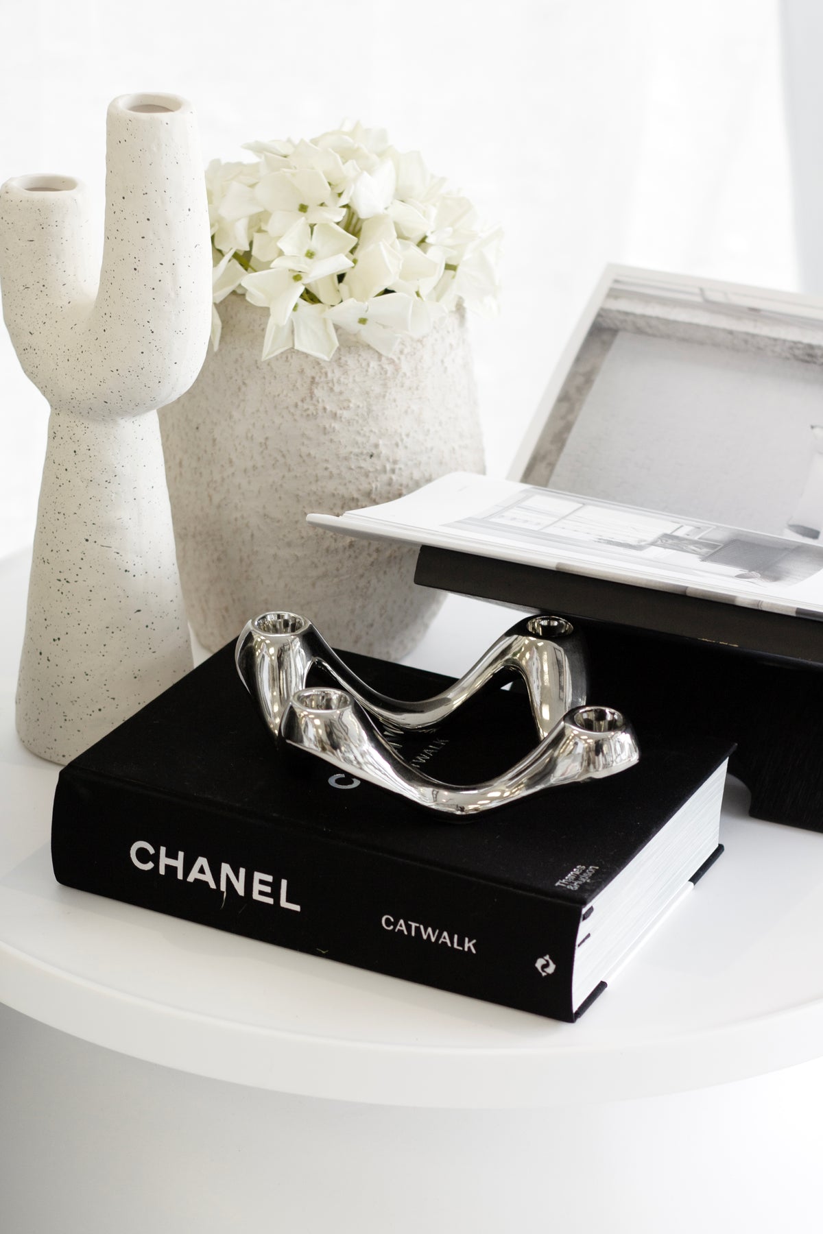 Chanel Catwalk coffee table book styled with sculptural vases and a silver candle holder for a modern, luxury interior look.