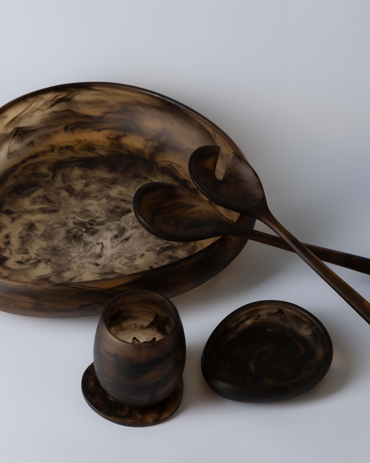 Chocolate tumbler on a resin coaster beside a small bowl, with salad servers in a large resin bowl