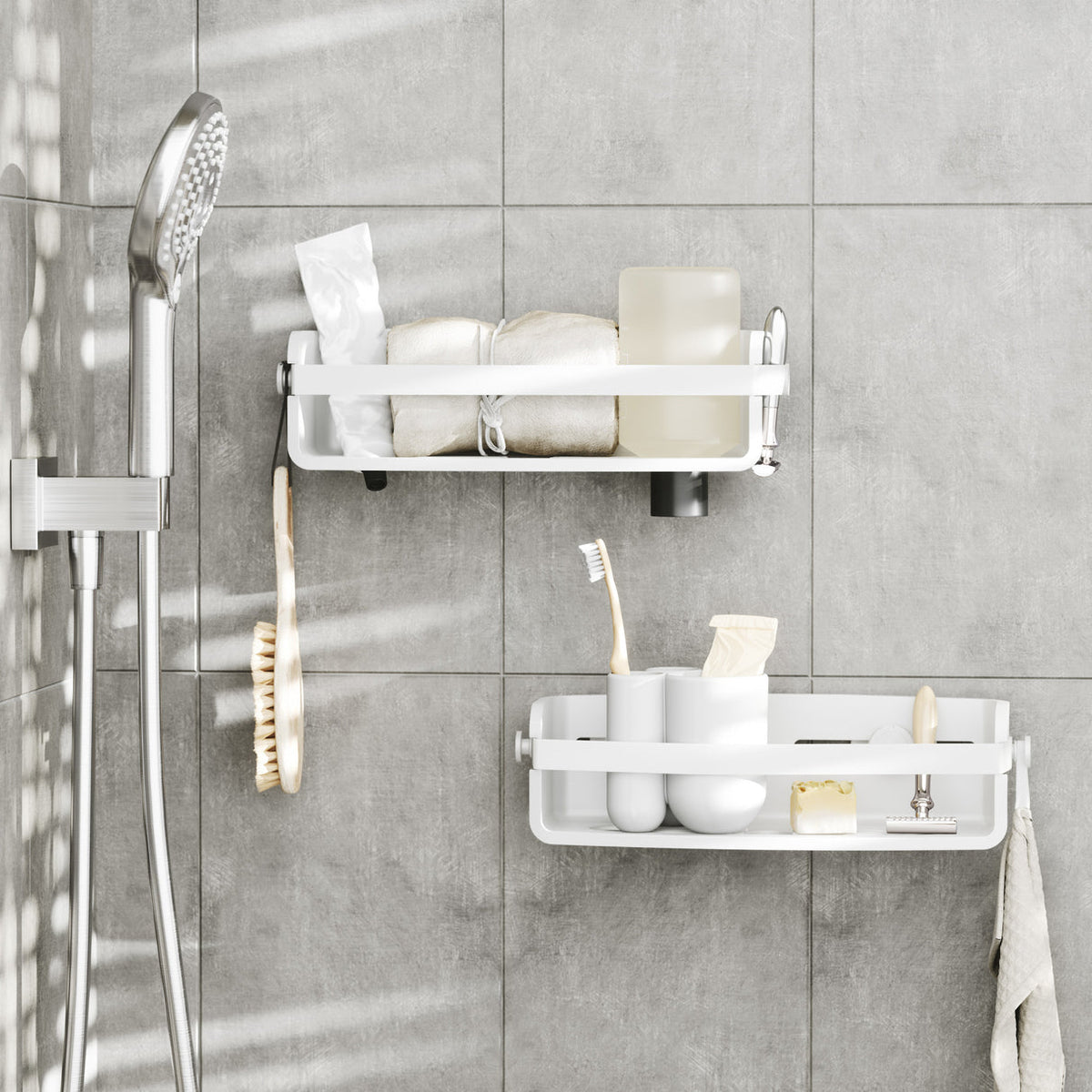 Two Umbra Flex shower bins in white in a tiled shower with toiletries and toothbrushes