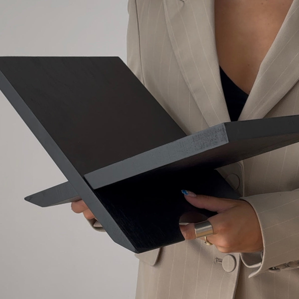 Black Como book stand held open to show its folding cross frame