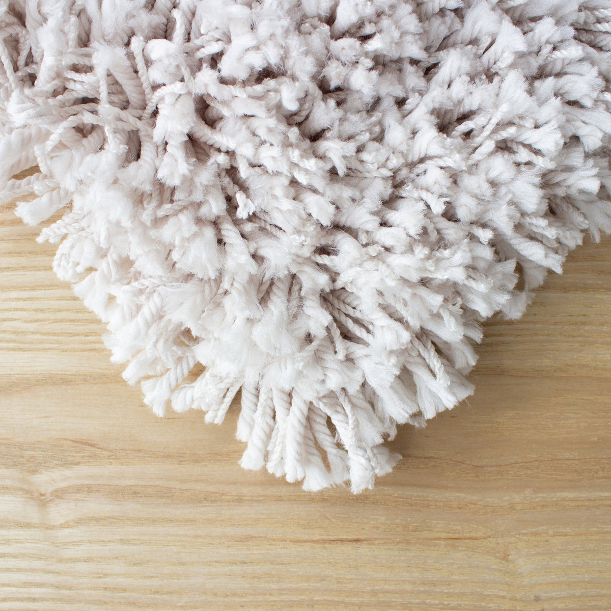 Corner of the beige shaggy rug on a pale timber floor