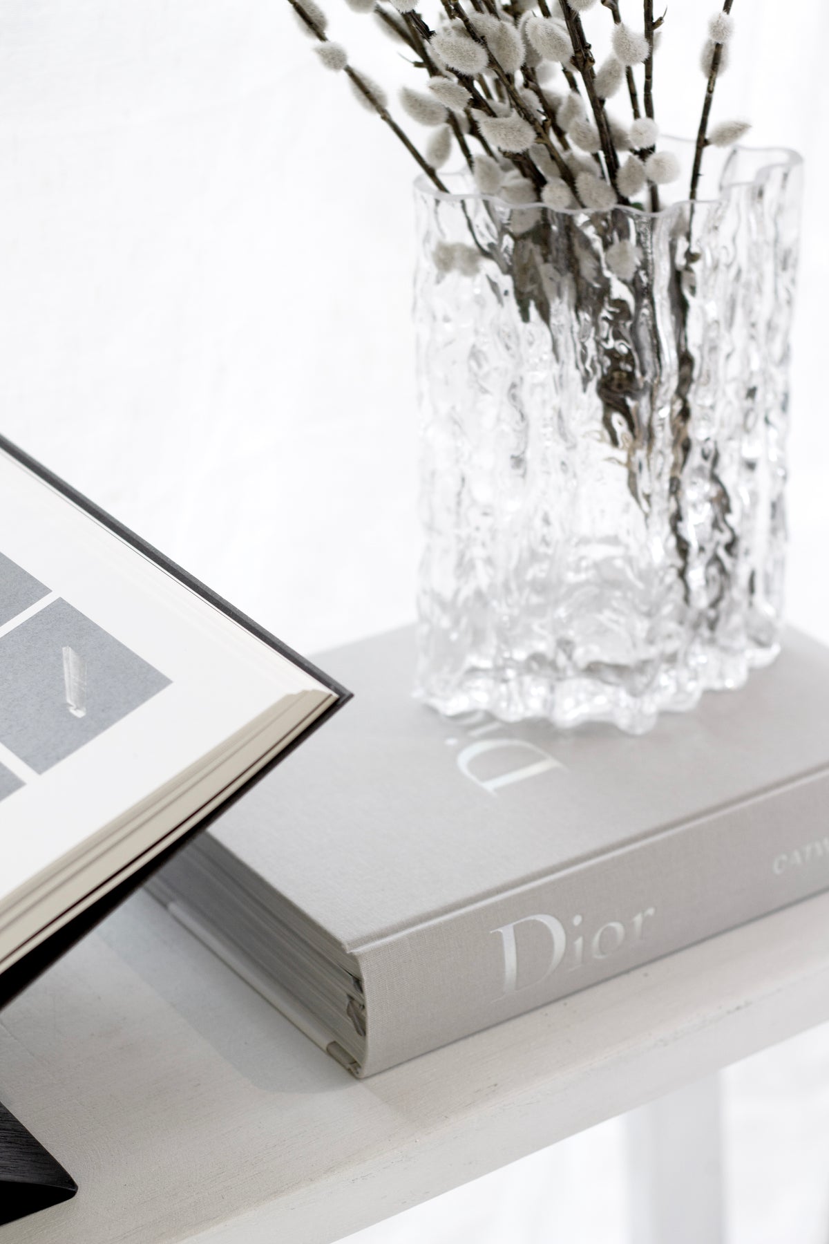 Dior Catwalk fashion book styled on a coffee table with flowers and modern decor.