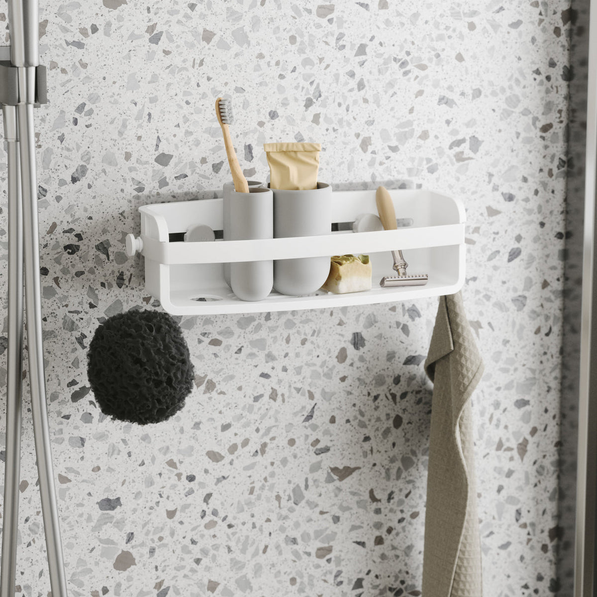 Umbra Flex shower bin in white on a terrazzo wall holding toothbrushes and cups