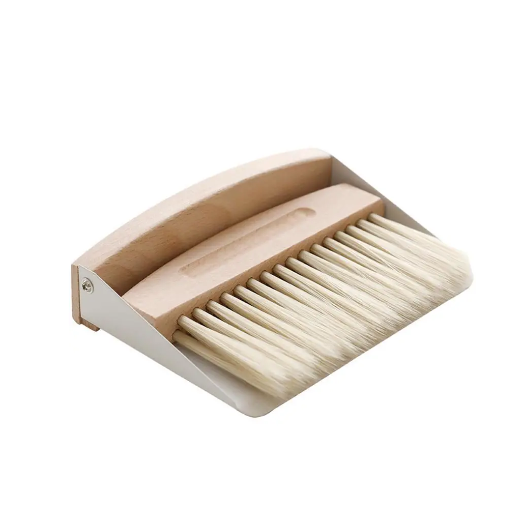 Tabletop dustpan and brush nested together at an angle on a plain white background