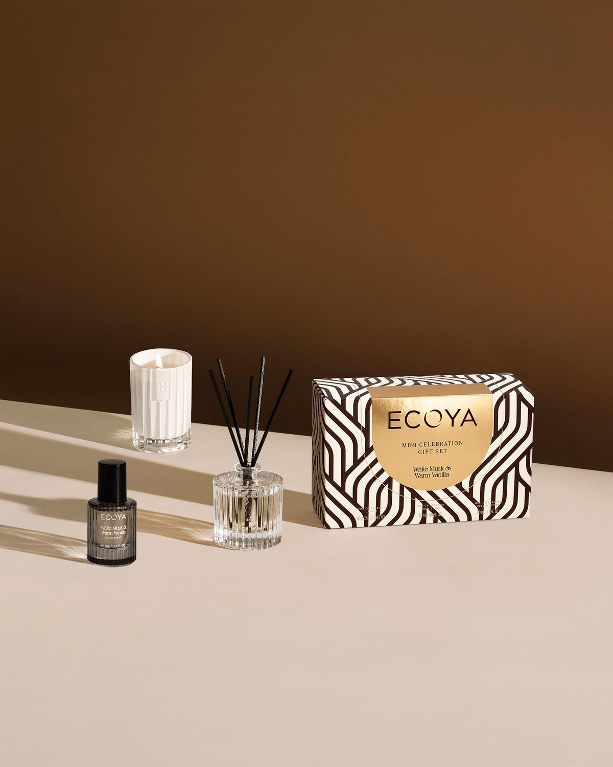 Ecoya Celebration White Musk and Warm Vanilla mini candle, diffuser and spray styled on stone