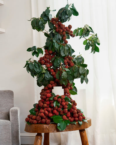 ECOYA Electric Wax Melter within a dramatic lychee and botanical tower installation on a timber stool, evoking the Guava & Lychee Sorbet Soy Wax Melt fragrance.
