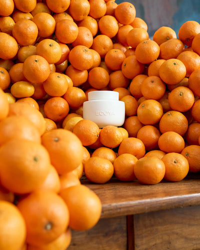 ECOYA Electric Wax Melter surrounded by fresh mandarins and oranges on a timber surface, evoking the Mandarin Gin Soy Wax Melt fragrance.