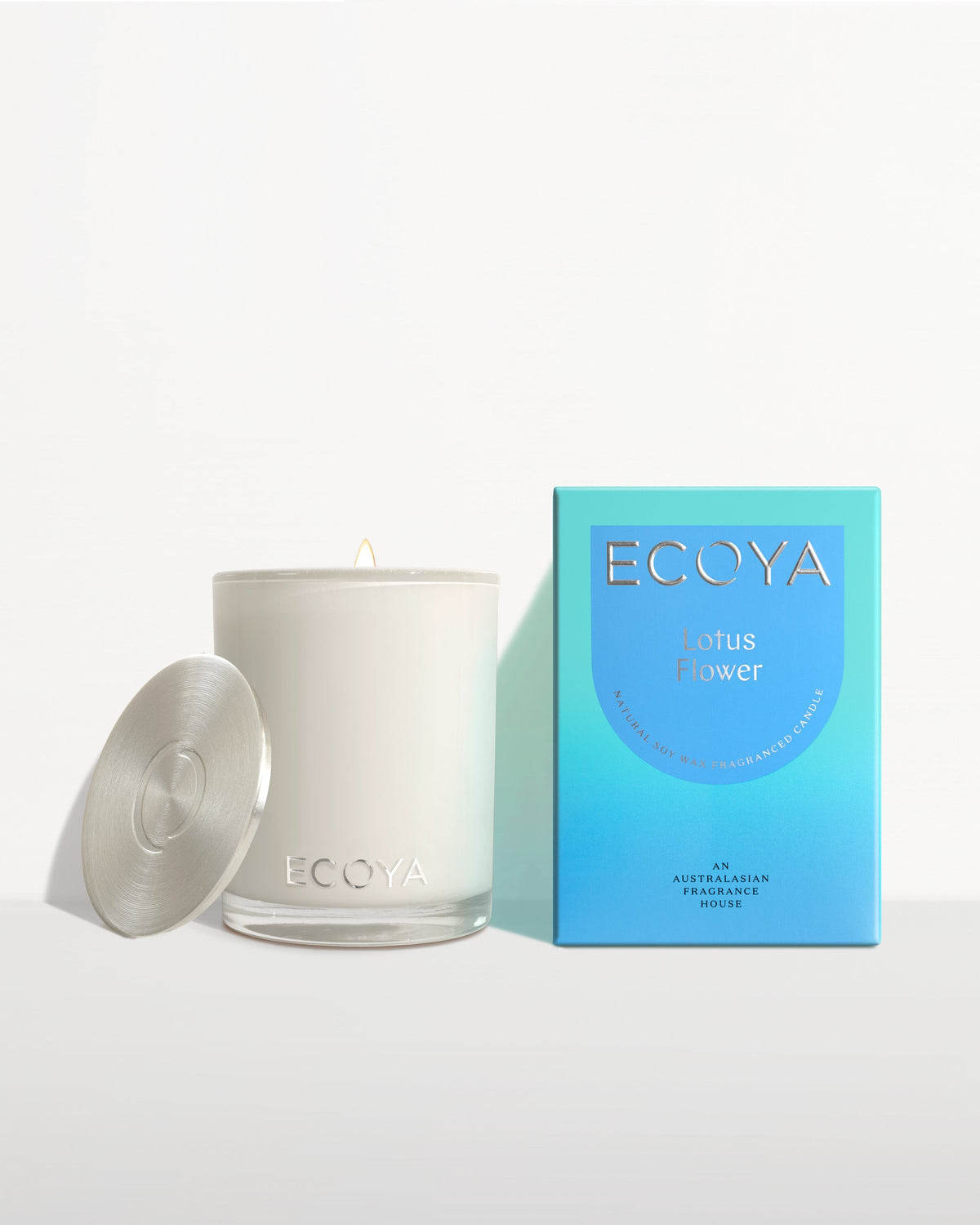 Ecoya Madison soy candle with its lid removed, shown beside its blue Lotus Flower gift box