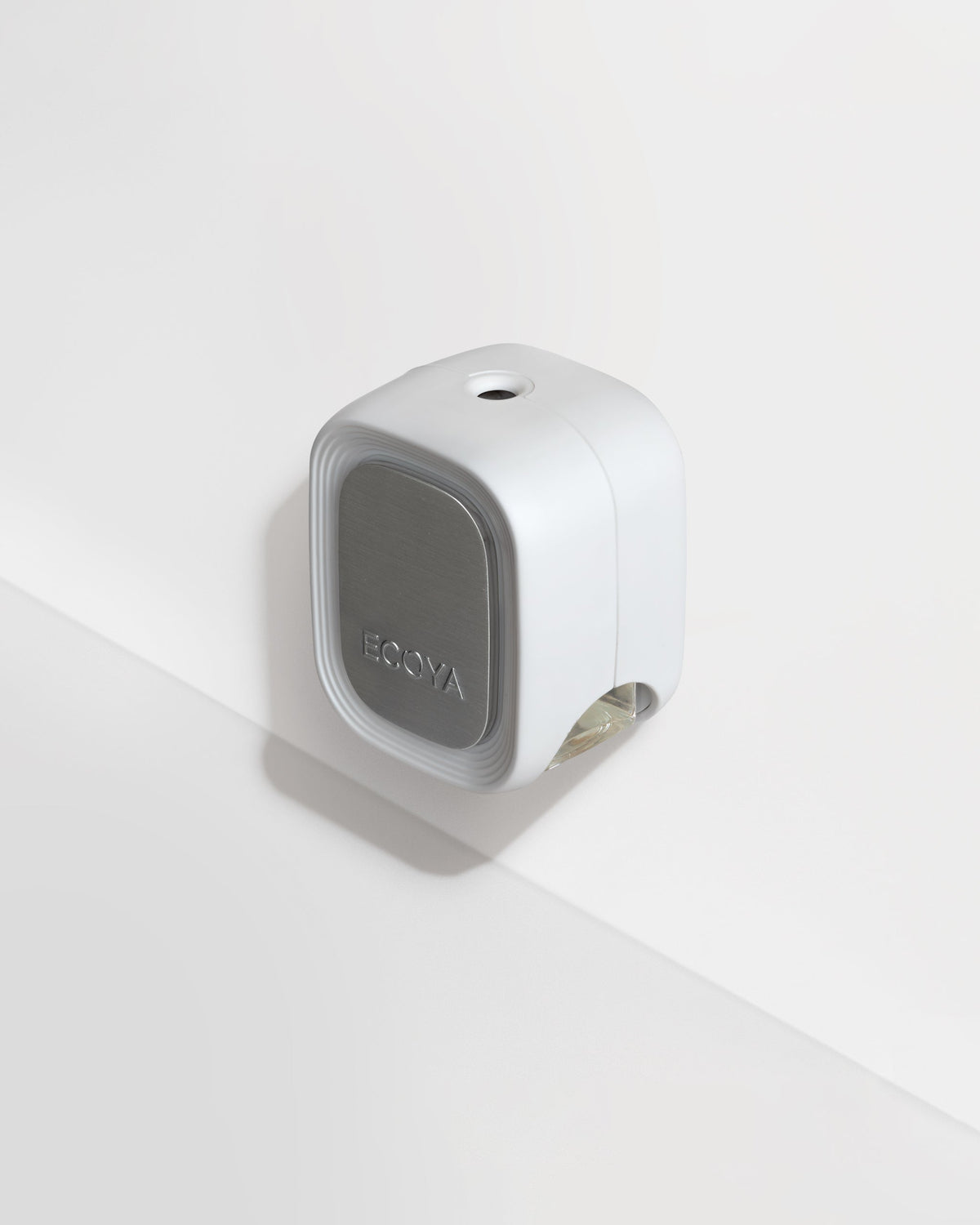 Close-up of the Ecoya Plug-In Diffuser on a white wall, showing the metallic faceplate and flask slot