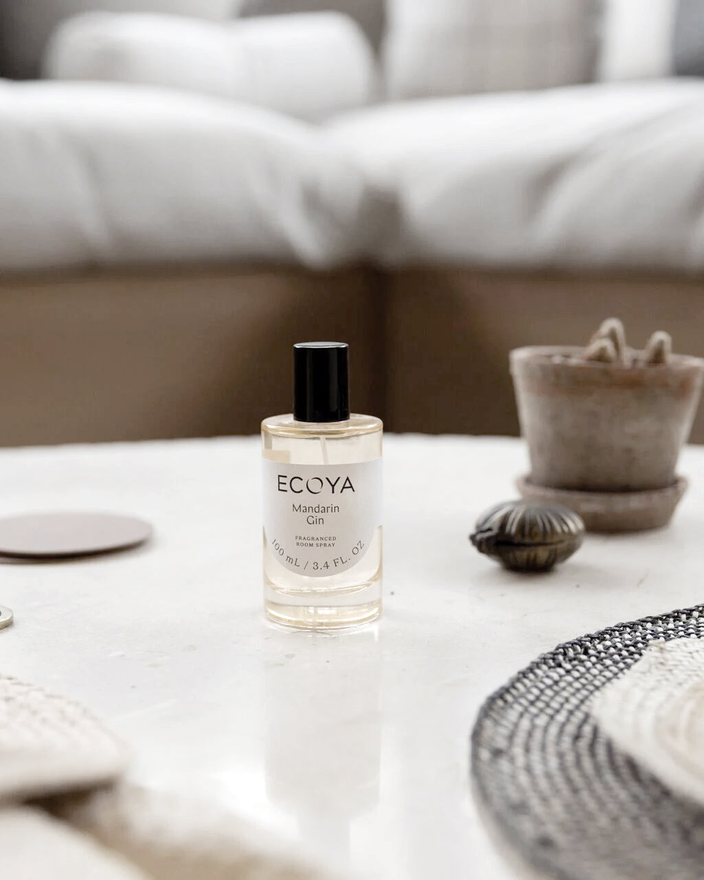 Ecoya room spray on a white coffee table in a soft neutral living room