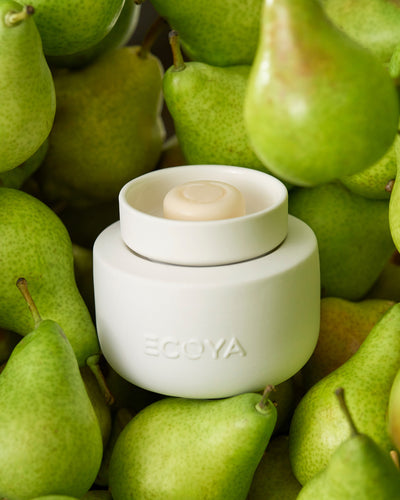 Close up of ECOYA Electric Wax Melter nestled among green pears, evoking the French Pear Soy Wax Melt fragrance.