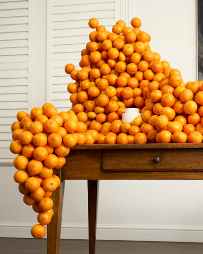 ECOYA Electric Wax Melter within a dramatic stacked mandarin and orange installation referencing the Mandarin Gin fragrance.