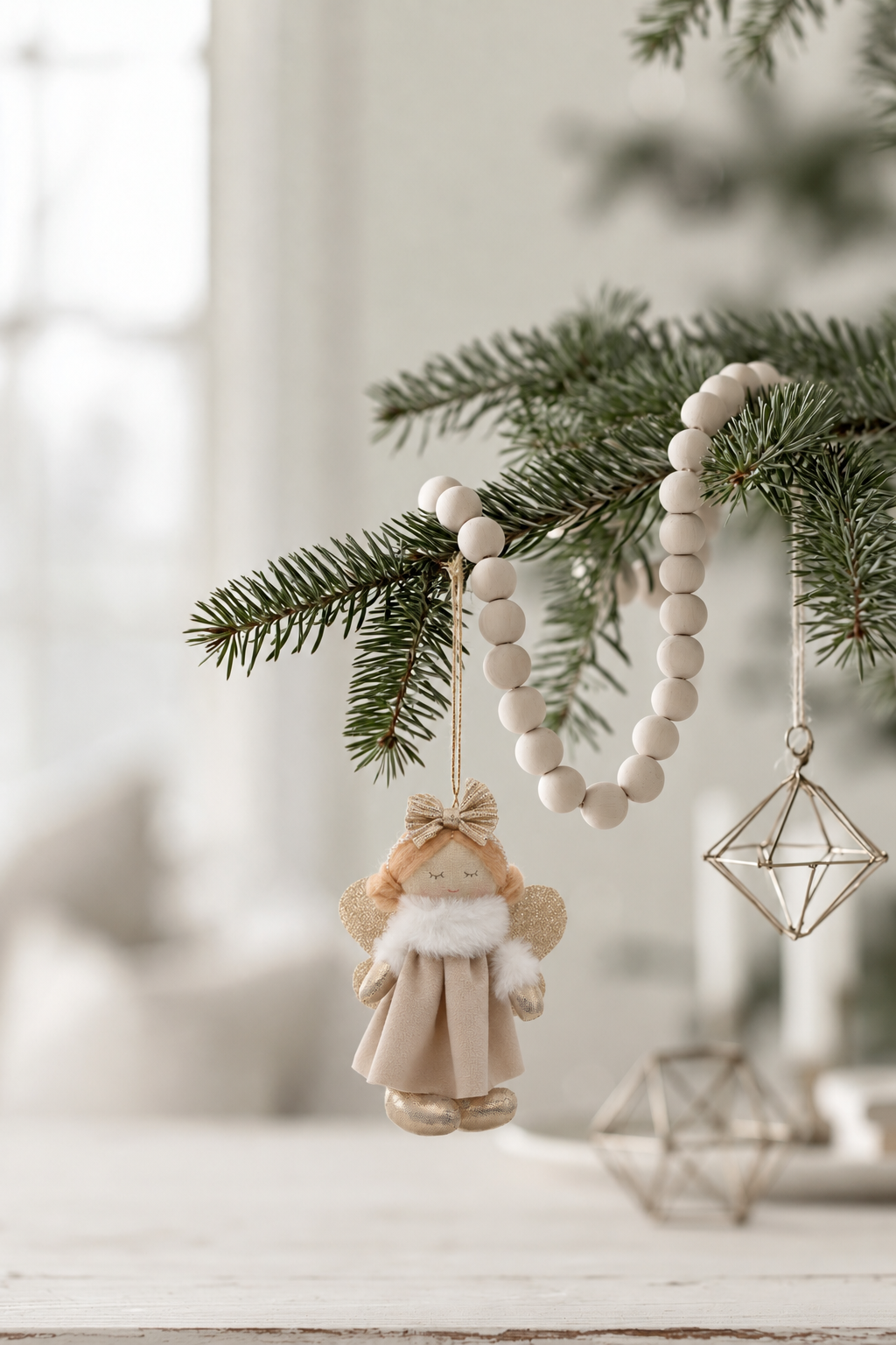 Edie hanging angel in latte velvet on a pine branch with a wooden bead garland and geometric ornaments