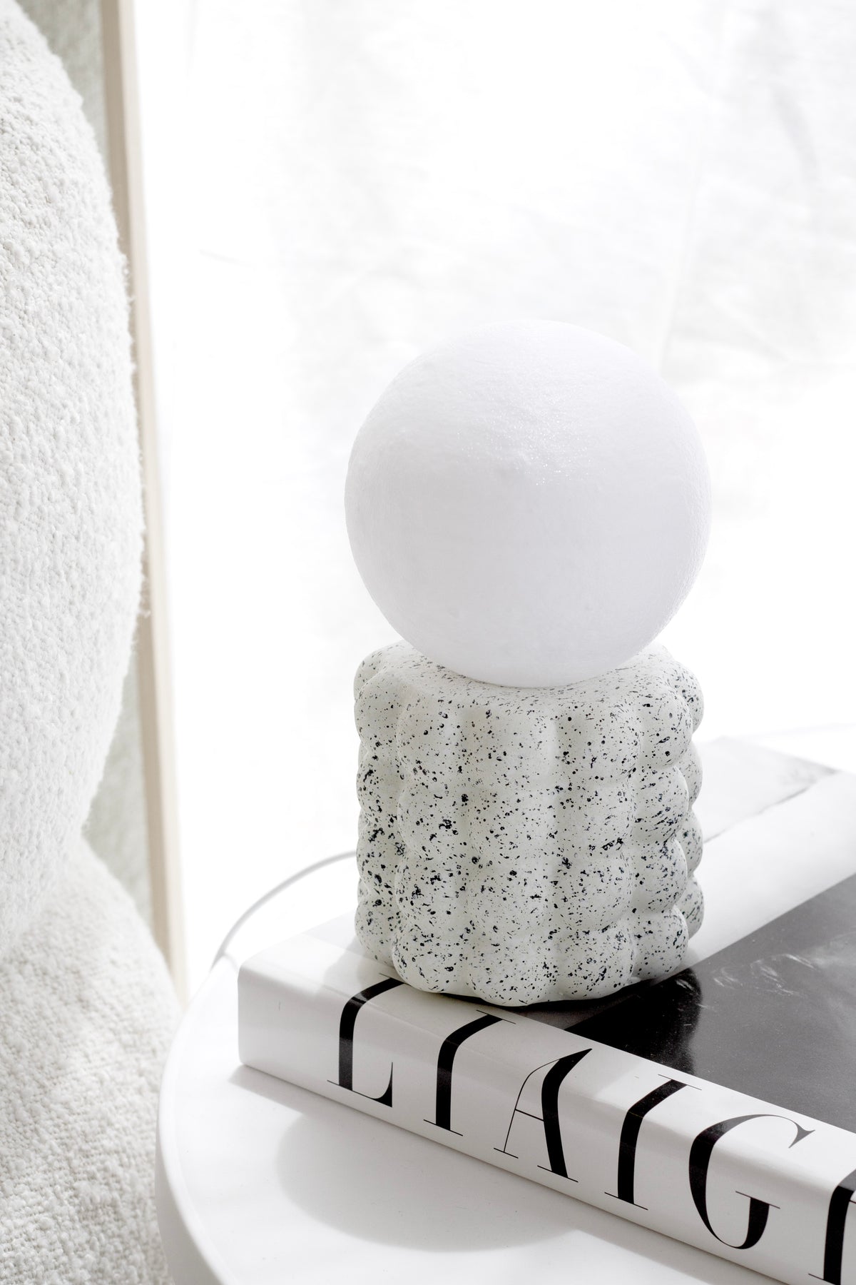 Elara Glow lamp unlit on a monochrome striped book on a round white side table