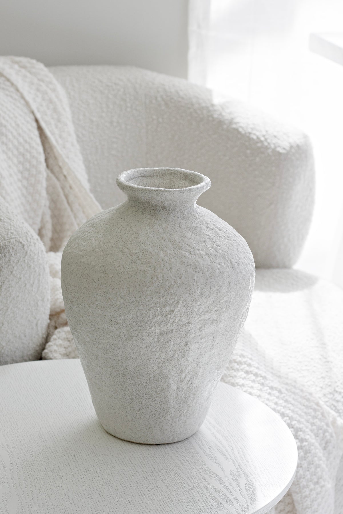 Lyra white stone-textured vase beside a boucle armchair