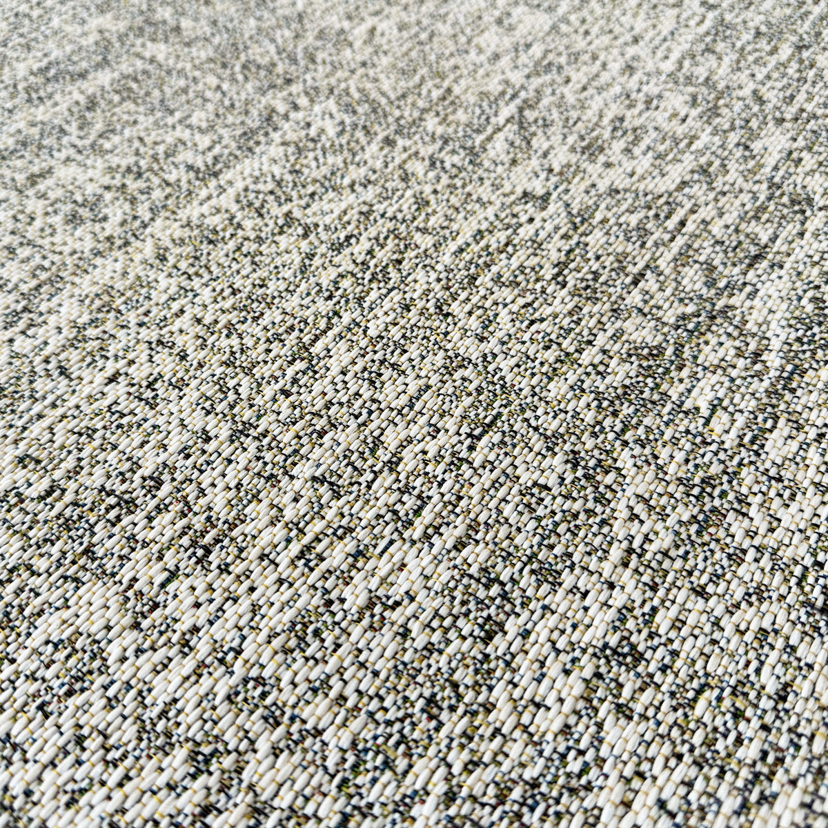 Close view of the flecked flat weave in brown, charcoal and cream