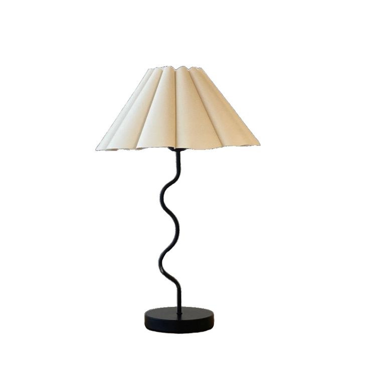 Wavy table lamp in black with a pleated off-white fluted shade and round base on a plain white background