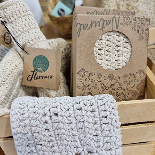 A box of Ecomax fair trade crocheted items, including a Cotton Face Cloth made from unbleached cotton, beautifully presented in a wooden crate.
