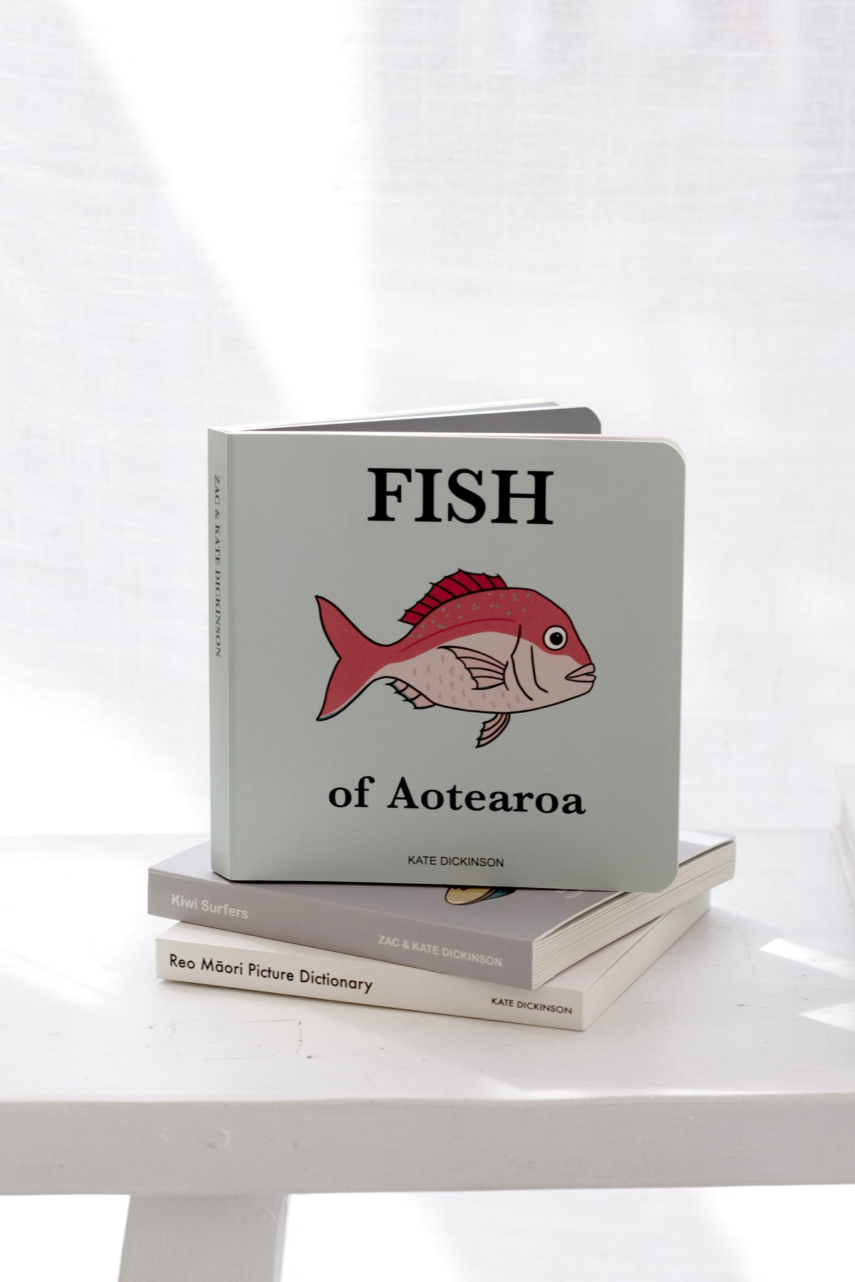 Fish of Aotearoa children’s board book by Kate Dickinson stacked on neutral books on white table