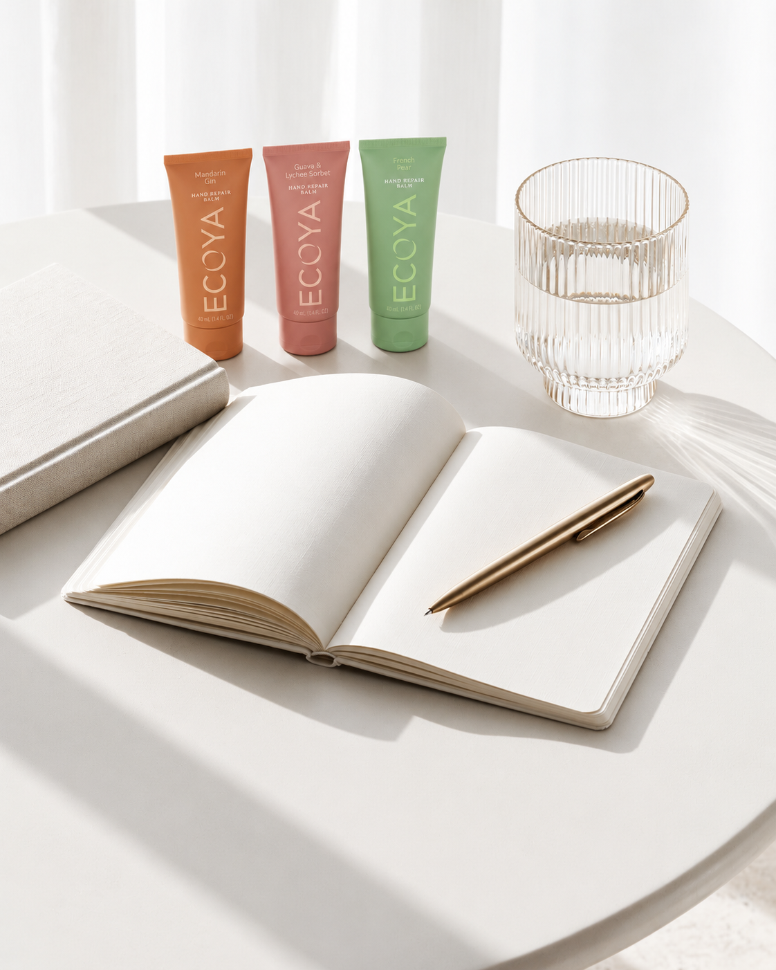 Ecoya Hand Repair Trio tubes standing on a white desk beside an open notebook