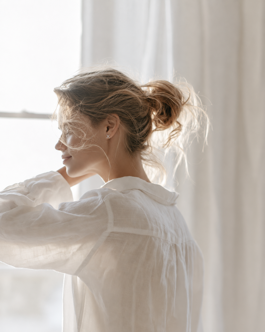 Woman by a sunny window wearing the Federation Kisses Studs in sterling silver