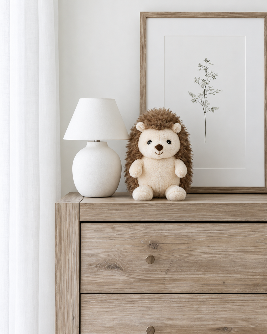 Hugo the Hedgehog soft toy by Lily & George sitting on a timber chest of drawers beside a white lamp