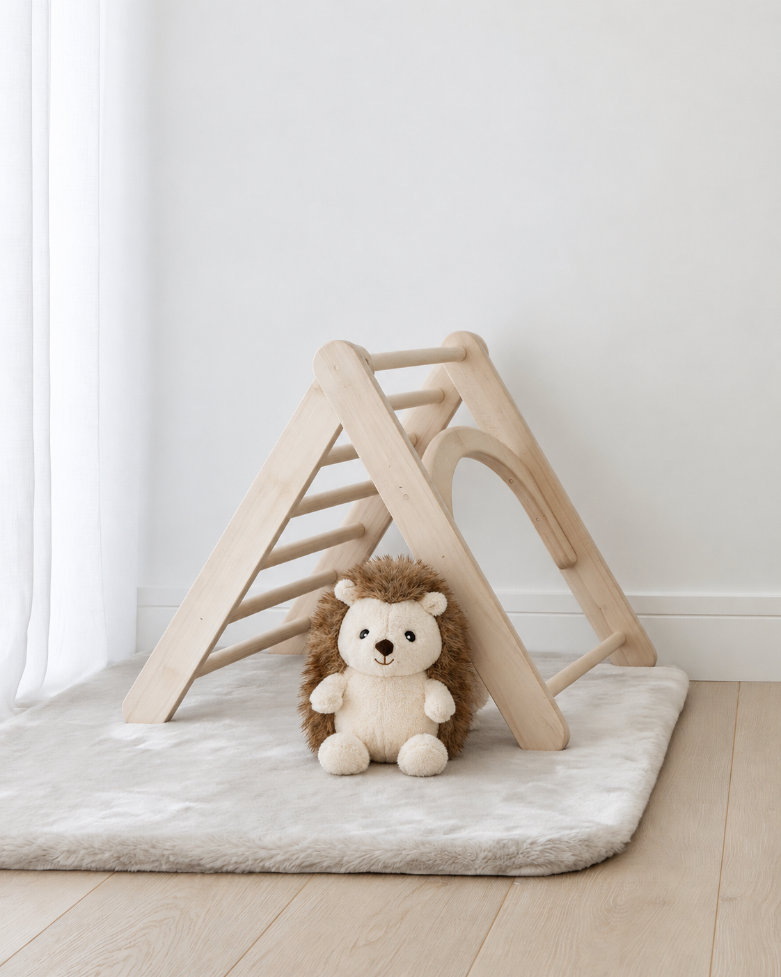 Hugo the Hedgehog mini soft toy by Lily & George sitting on a soft play mat in front of a timber climbing triangle