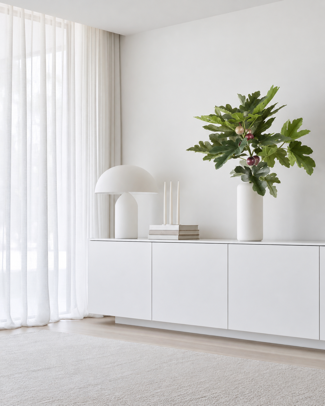 Fig leaf spray with figs in a tall white vase on a white sideboard