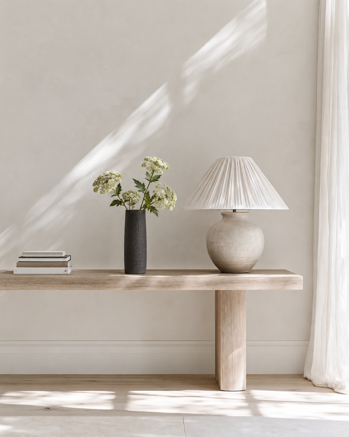 Queen Anne's Lace stems in light green sitting low in a charcoal vase on an oak console
