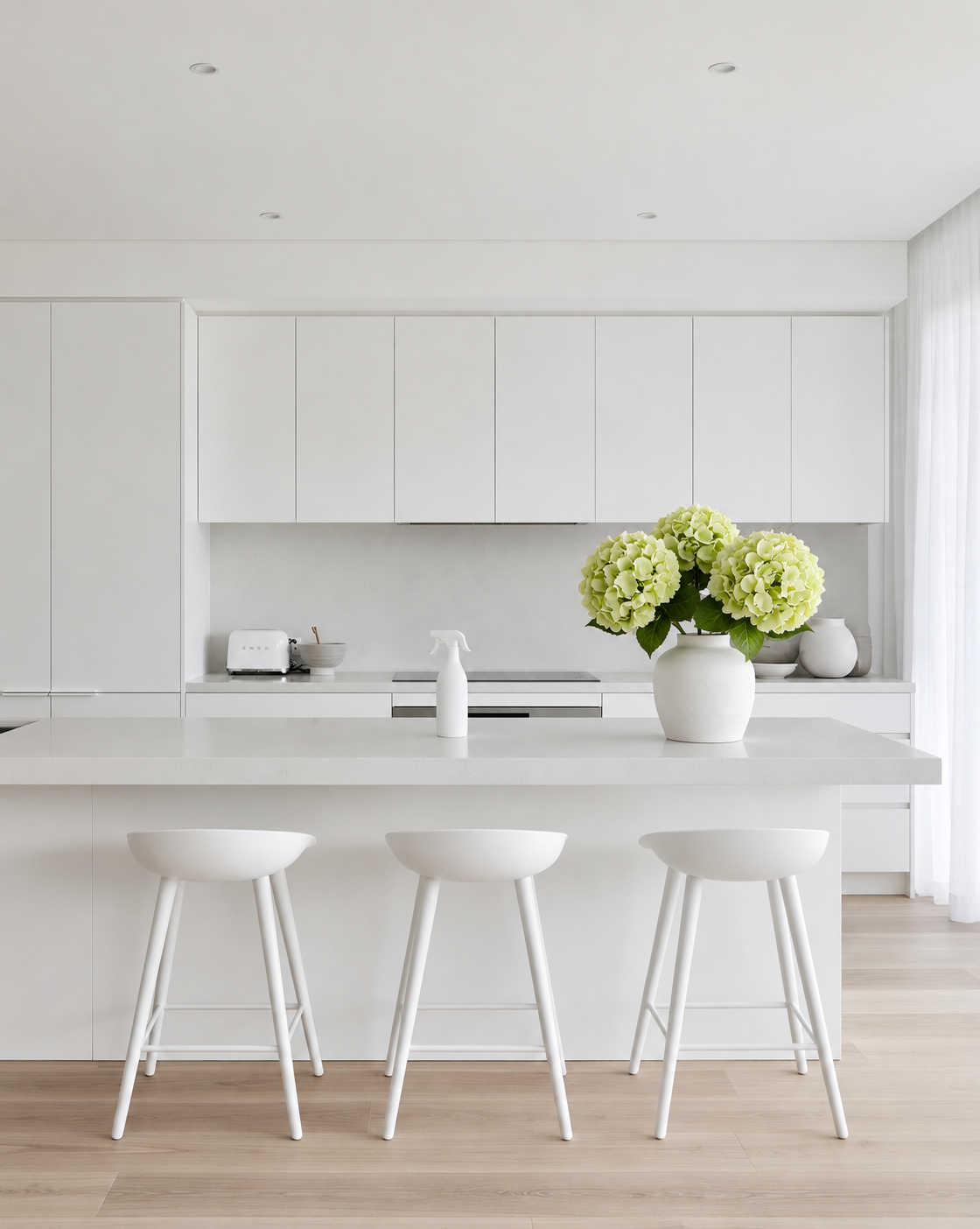 Three Dutch Green Hydrangea stems in a white vase on the white island